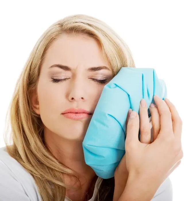 woman holding an ice pack against jaw